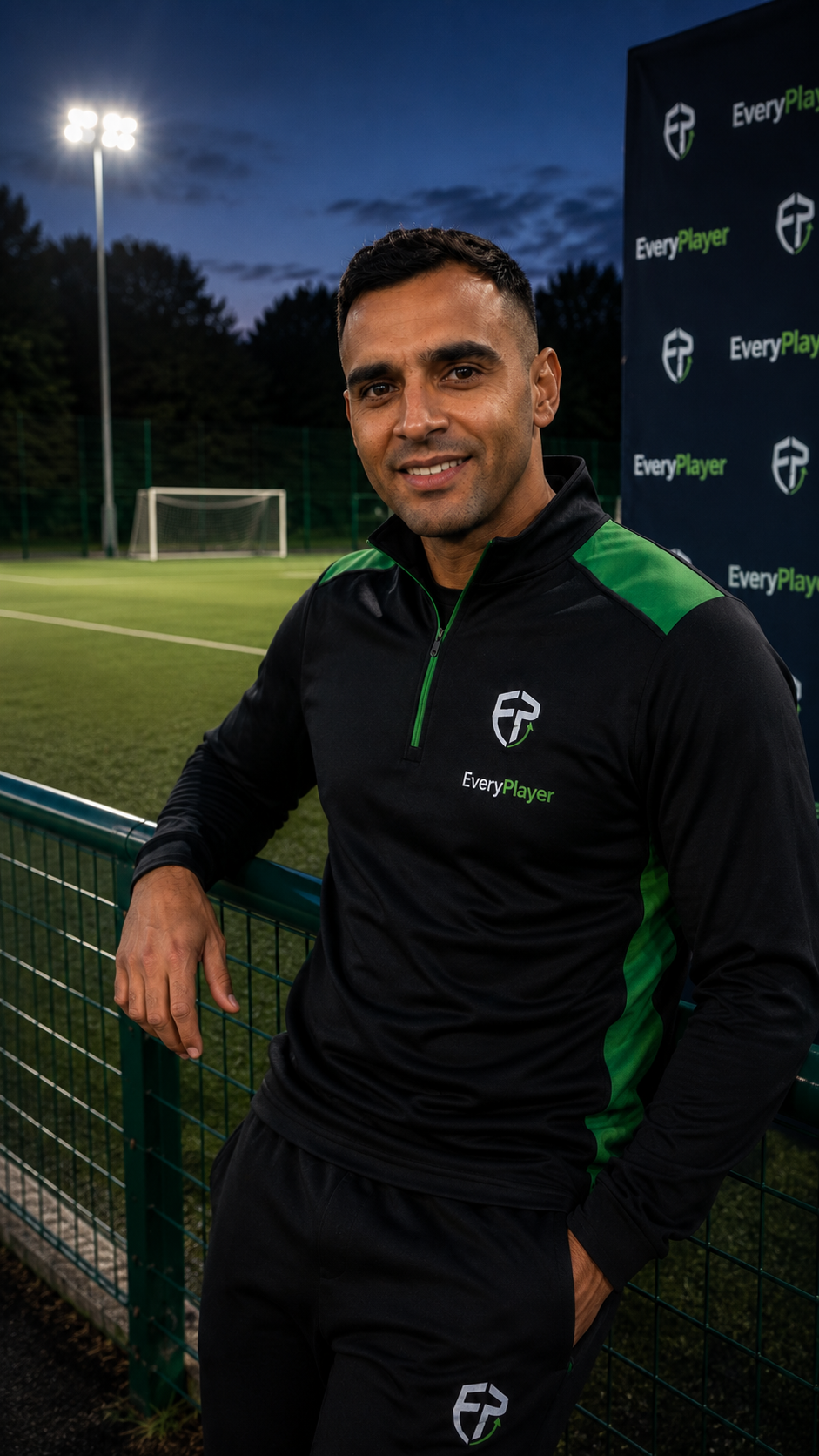 EveryPlayer representative team coach beside a floodlit pitch